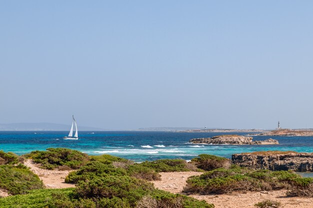 Paisaje marino de la costa de Ibiza con un hermoso mar azul y un yate de vela