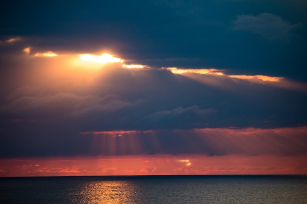 Un paisaje marino fascinante con nubes dramáticas y luz solar entre ellos.