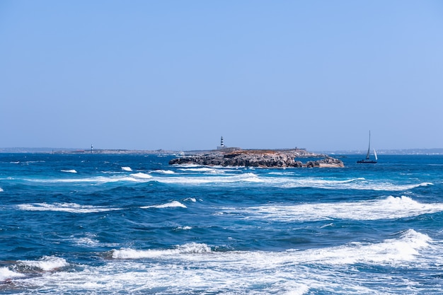 Paisaje marino con un hermoso mar azul y un faro frente a la costa de la isla de Formentera. Islas Baleares. España