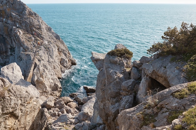 Paisaje marino, mar y montañas, rocas y árboles tropicales, gruta de piedra salvaje, agua rompiendo en las rocas