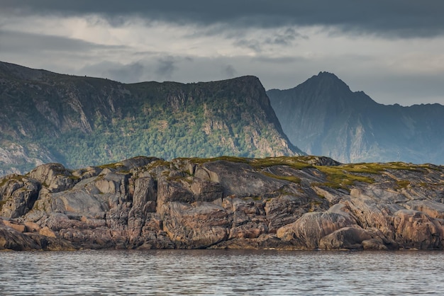 Paisaje marino noruego costa rocosa con cielos dramáticos el sol se rompe a través de las nubes acantilados escarpados pequeñas islas iluminadas por el sol