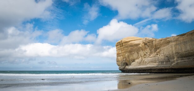 Paisaje marino panorámico con cielo azul y playa de túnel de acantilado de arenisca nueva zelanda