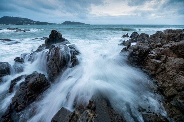 Paisaje marino de poderosa ola grande golpeando y chapoteando en la roca de la costa en un día nublado en Phuket.