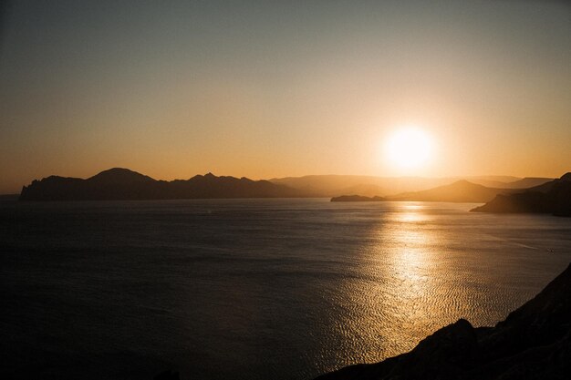 Paisaje marino Puesta de sol en la costa Mar de tarde El sol está debajo del horizonte Rocas Naturaleza hermosa