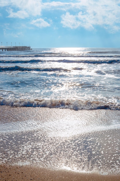 Un paisaje marino vertical Mar con olas y muelle en un soleado día de invierno