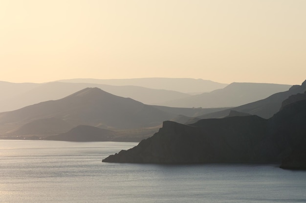 Paisaje marino con una vista panorámica de las montañas. Puesta de sol en colores amarillos