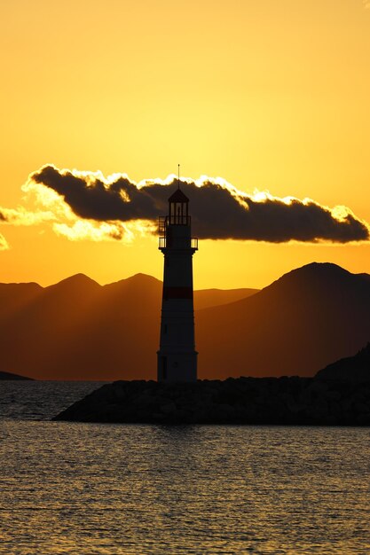 Foto paisaje marítimo al sol faro y navegaciones en la costa la ciudad costera de turgutreis y el sol espectacular