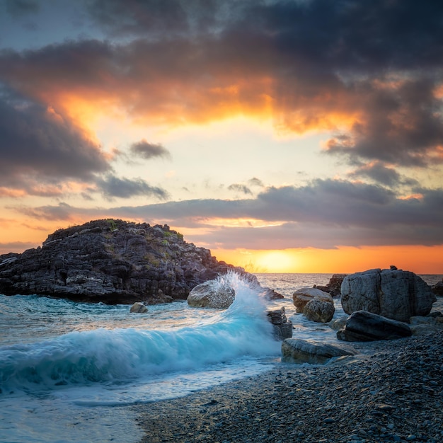 Foto paisaje marítimo mar océano ola golpea la roca en la playa agua del mar salpicaduras hacia el cielo con el sol sunset sunset en el mar tormenta paisaje marino