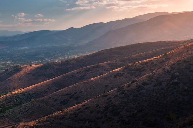 Paisaje de montaña al atardecer con cimas de colinas iluminadas en primer plano, Peloponeso, Grecia