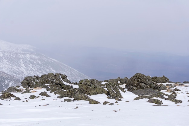 Paisaje de montaña ártica con rocas de granito que sobresalen de debajo de la nieve en primer plano