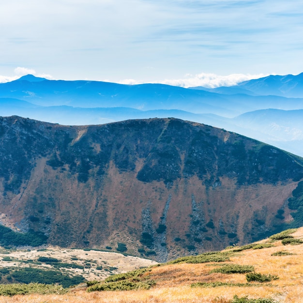 Paisaje de montaña con campo de hierba seca y cielo azul