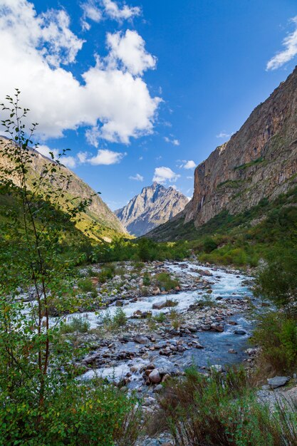 Paisaje de montaña con cascada y turistas.