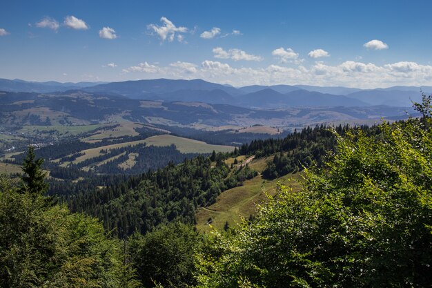 Paisaje de montaña en un día soleado. Cielo con nubes, montañas en la bruma, bosque.