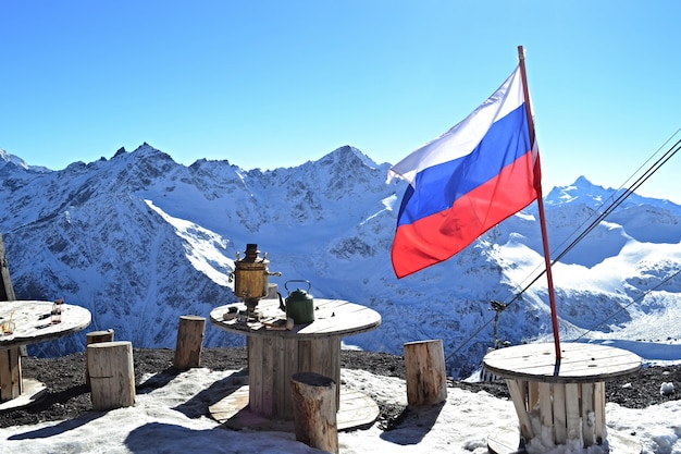 Paisaje de montaña de invierno, bandera rusa, samovar y cafés en las montañas