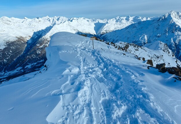 Paisaje de montaña de invierno desde la cima de la colina con ventisquero (Tirol, Austria).