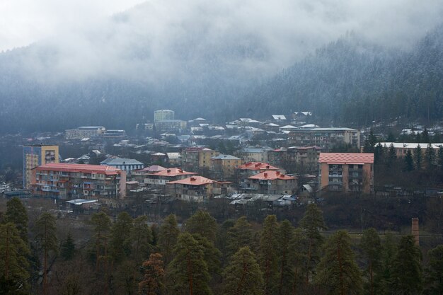 Paisaje de montaña de invierno. Pequeño pueblo entre montañas. Una nube se cierne sobre la ciudad.