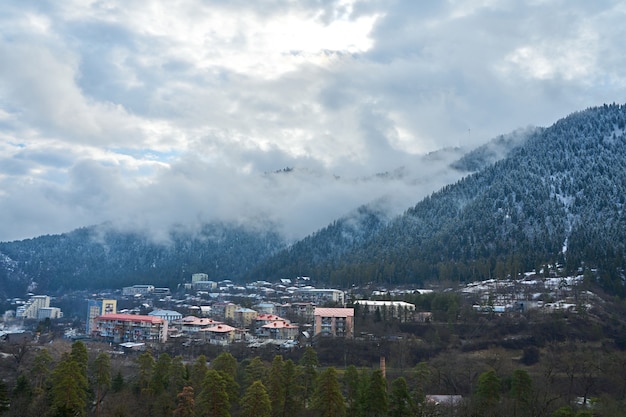 Foto paisaje de montaña de invierno. pequeño pueblo entre montañas. una nube se cierne sobre la ciudad.