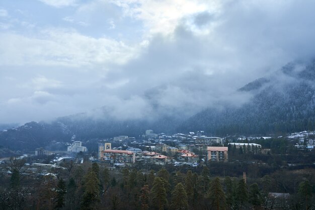 Paisaje de montaña de invierno. Pequeño pueblo entre montañas. Una nube se cierne sobre la ciudad.