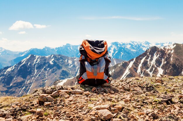 Paisaje de montaña nevada. mochila de turista se encuentra en las rocas en la cima de las montañas.