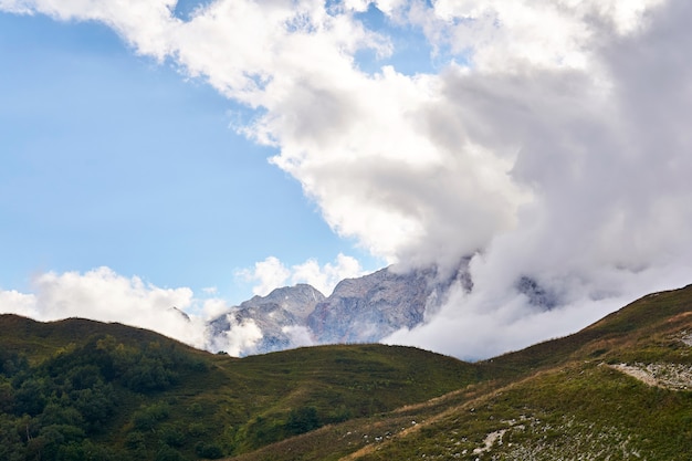 Paisaje de montaña con nubes que se elevan desde el valle más allá del paso cercano