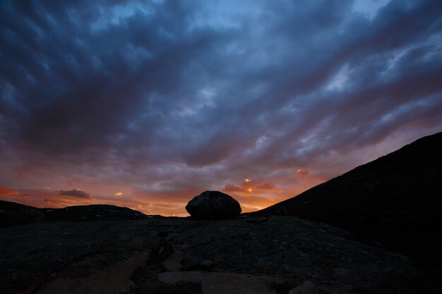 Paisaje de montaña, paisaje noruego. piedra grande en el fondo de la puesta del sol