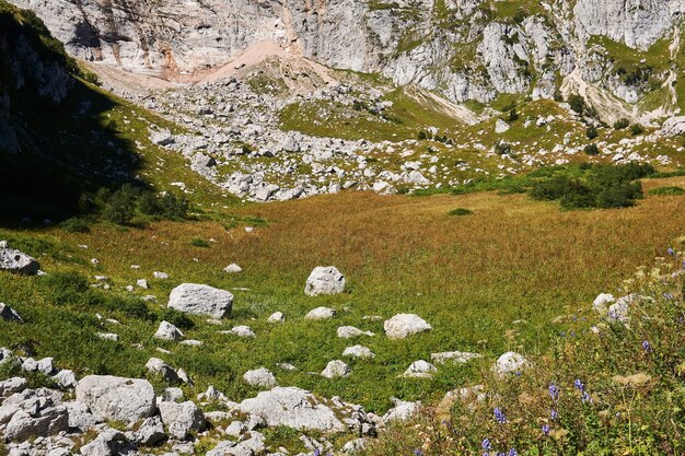 Paisaje de montaña: pequeño valle entre escarpados acantilados con una pradera alpina otoñal