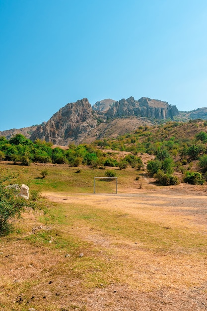 Paisaje de montaña y una portería de fútbol sobre un fondo de cielo azul