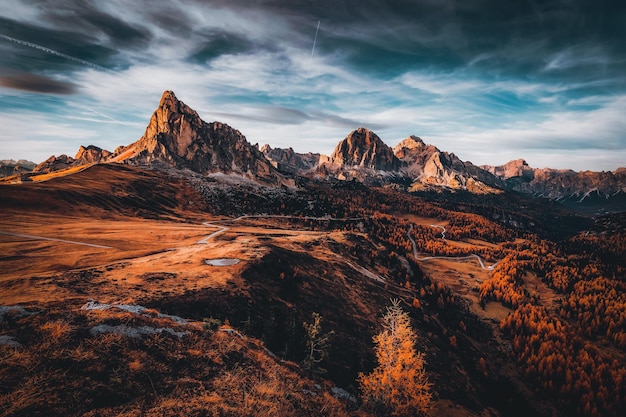 Un paisaje de montaña con una puesta de sol y un cielo nublado