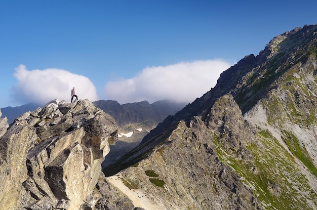 Paisaje de montaña con un turista de pie sobre una roca.