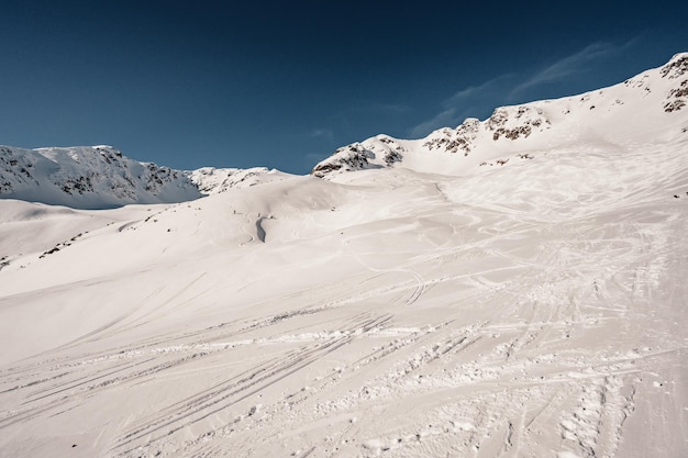 Paisaje de montañas alpinas con nieve blanca y cielo azul Puesta de sol de invierno en la naturaleza Árboles helados bajo la cálida luz del sol Maravilloso paisaje invernal