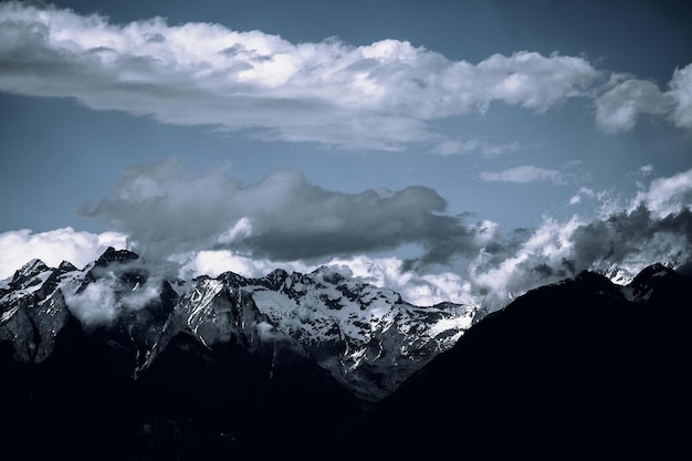 Paisaje de montañas rocosas cubiertas de nieve bajo un cielo nublado oscuro