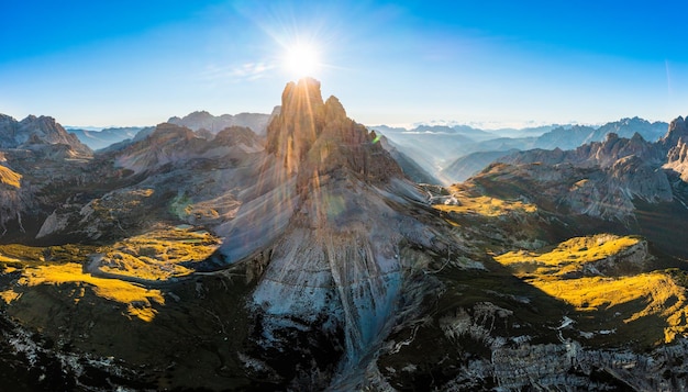 Foto paisaje montañoso de tres picos de lavaredo al amanecer picos dentados soleados y amplias colinas sombreadas