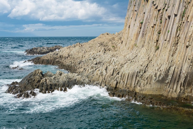 Paisaje natural con un acantilado de basalto columnar plegado en la orilla del mar