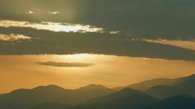 Paisaje natural de montaña con picos nebulosos iluminados amanecer sobre las montañas en tiempo real