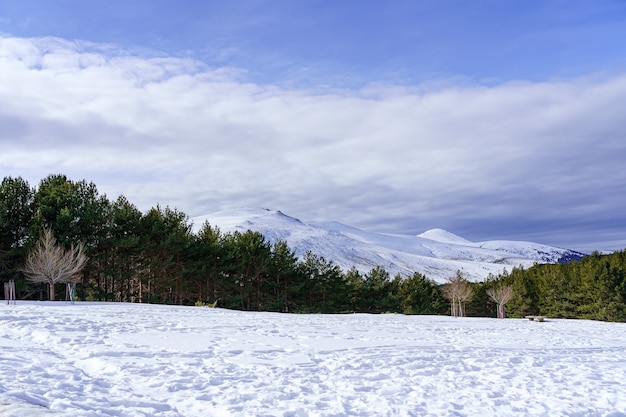 Foto paisaje nevado en la montaña de madrid con sol, cielo azul y alta montaña. morcuera.