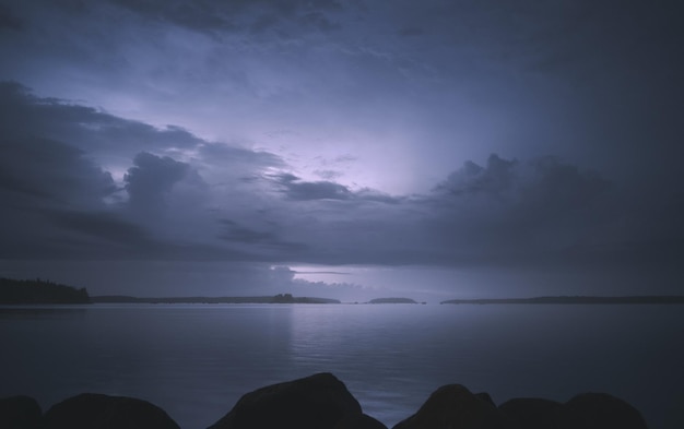 Paisaje nocturno Lake Shore Las nubes están iluminadas por una tormenta que se aproxima