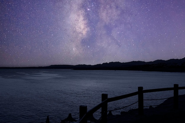 Paisaje nocturno del Mar Rojo y las montañas del Sinaí contra el fondo del cielo nocturno con estrellas y la península de Sinaí de la Vía Láctea