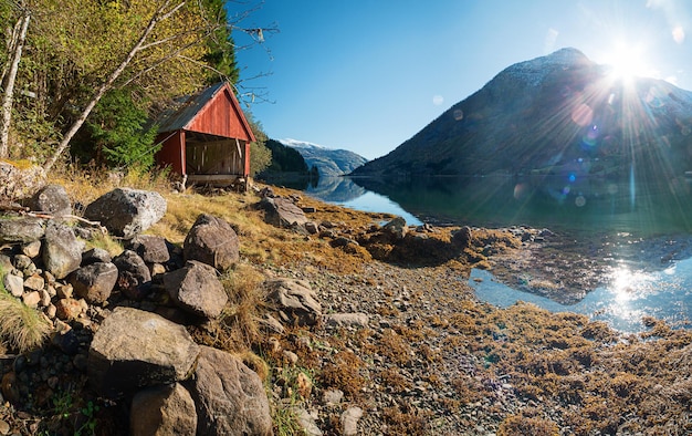 Paisaje noruego con fiordos, montañas y almacenamiento de botes de madera tradicionales en la orilla