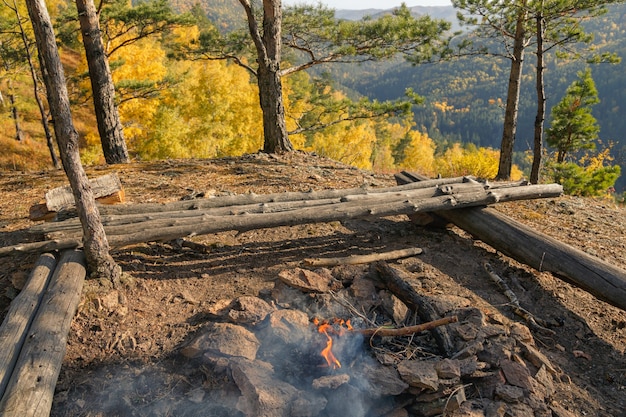 Paisaje otoñal con una hoguera ardiente en primer plano y montañas cubiertas de bosques