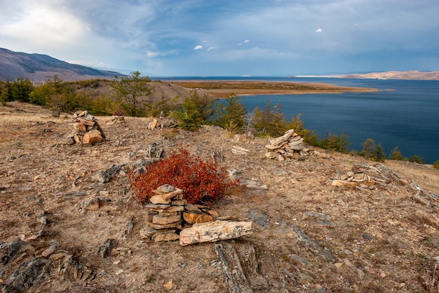 Paisaje otoñal con el lago Baikal y montones de piedras en primer plano