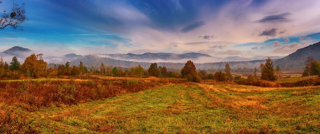 Paisaje de otoño brumoso rural con árboles rojos y nubes Estado de ánimo de silencio de otoño estacional Vista panorámica