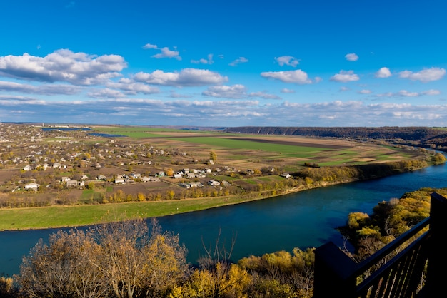 Paisaje de otoño - río, cielo con nubes, campos.