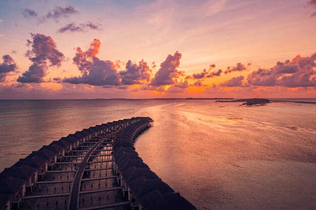 Paisaje panorámico del atardecer aéreo lujosas villas acuáticas tropicales hermosa playa de la isla naranja