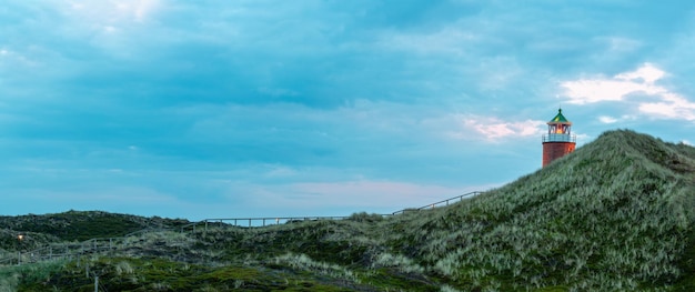 Paisaje panorámico en la isla de Sylt en el Mar del Norte Alemania Hermosos paisajes naturales con colinas de hierba de marram y un faro en la isla del Mar del Norte