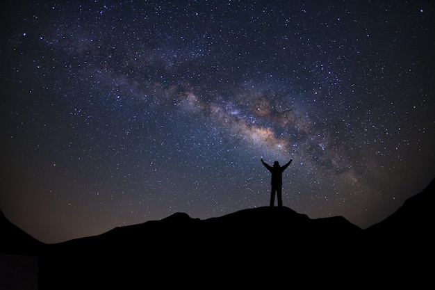 Paisaje panorámico con vía láctea Cielo nocturno con estrellas y silueta de un hombre deportivo de pie