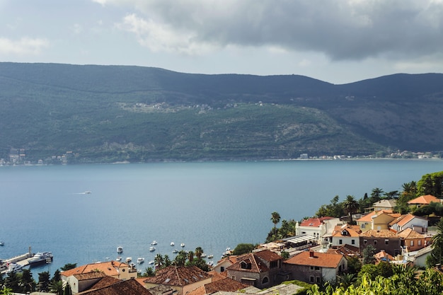 Paisaje de plan urbano en un clima cálido y soleado en la ciudad de Kotor. La ciudad está rodeada de montañas y rocas, al pie de las cuales el mar se desborda.