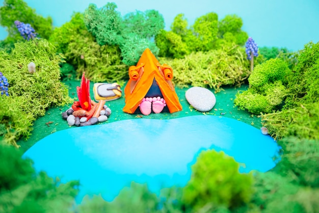 Paisaje de plastilina con carpa, fogata y mochila en medio del bosque