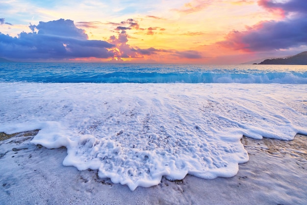 Paisaje de playa con idílico cielo degradado al atardecer y mar azul con espuma blanca
