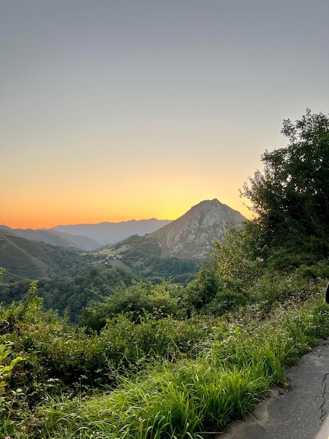 Paisaje de un pueblo rodeado de vegetación al atardecer Paisaje de montañas con vegetación al atardecer Vista de un pequeño pueblo rodeado de un volcán y vegetación al atardecer