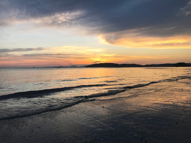 Paisaje de puesta de sol, arena y olas en la playa.